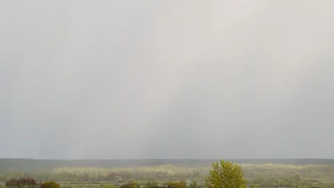 A large blue cloud in the sky against the backdrop of a green forest, field and Stock Footage 296578897