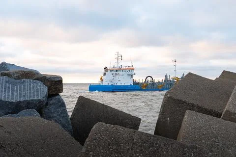 Large Blue Dredger Ship Navigating Ocean Near Breakwater Stock Photos