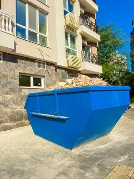 Large blue dumpster filled with building debris outside a residential build.. Stock Photos