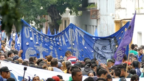 Large blue flag held up over people's head during immobilised protest Stock Footage 100195004