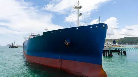 Large Blue Industrial Cargo Ship Docked At A Maritime Terminal Under Clear .. Stock Photos
