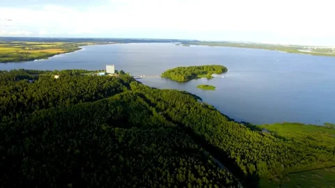 Large blue lake surrounded by dense green pine forest Stock Footage 333829669