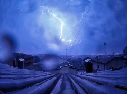 Large blue lightning over the rooftops during a thunderstorm Stock Photos