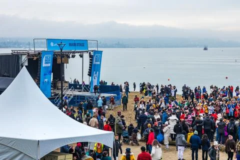 Large blue main stage with crowd of hundreds gathered on English Bay beach .. Stock Photos