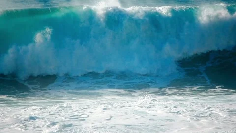 Large blue ocean wave crashing onto the sandy beach shore Видео 339132560