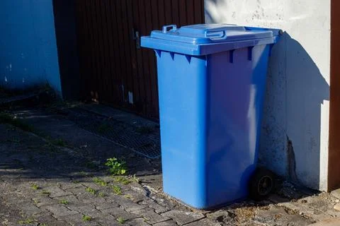 Large blue plastic wheelie bin for paper and cardboard recycling standing out Stock-Fotos