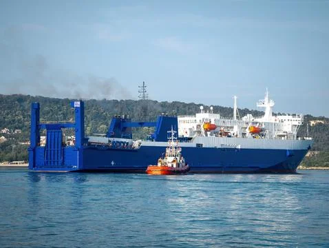 Large blue Ro-Ro freight ferry assisted by tugboat entering harbor Stock-Fotos