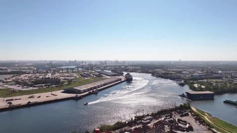 A large boat, identified as a barge, is seen traveling down a river next to a ci Stock Footage 287535597