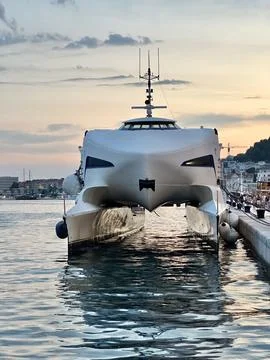 Large boat rests at dock during sunset in coastal area with calm water and Photos