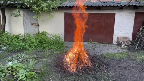 Large bonfire of dry branches near old garages Stock Footage 282532376