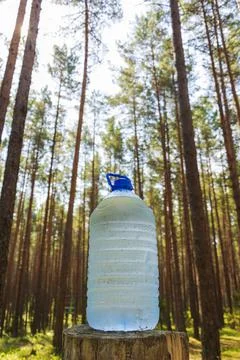 A large bottle of fresh clean drinking water is standing on a stump in the fo Stock Photos