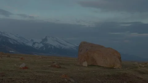 Large boulder in open steppe with snow mountains background Vidéo 333953104