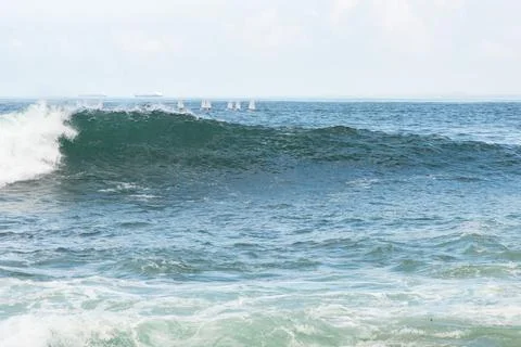 Large breaking wave with boats in the background Stock Photos