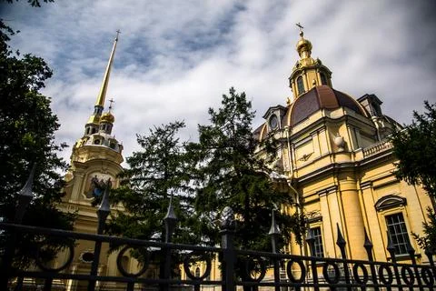 A large brick building featuring a clock tower stands tall behind a fence Stock Photos