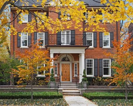 Large brick house surrounded by trees with fall colors Stock Photos