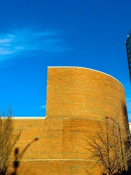 A large brick wall stands tall against a bright blue sky. The wall has a curv 스톡 사진
