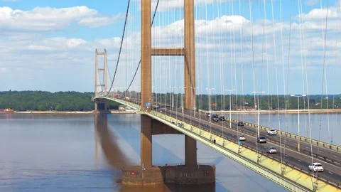 Large bridge spans wide river beneath clear blue sky Vidéo 343529488