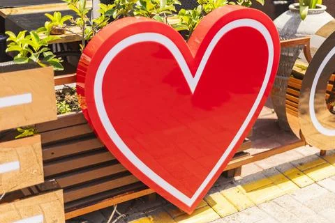 A large, bright red heart shape stands out in an open area filled with gree.. Stock Photos