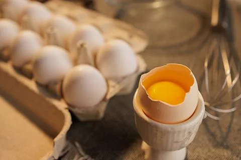 Large broken chicken egg in a special container on the background of a box .. Stock Photos