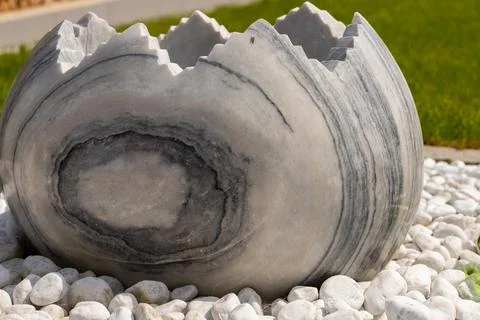 Large broken marble egg as a water fountain in a stone bed Stock Photos