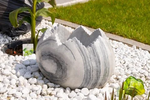 Large broken marble egg as a water fountain in a stone bed Stock Photos
