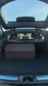 Large brown organizer box inside a clean modern car trunk. Open trunk of a .. Stock Photos