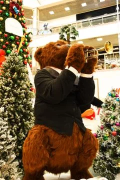 A large brown teddy bear in a jacket plays the trumpet. The bear stands near Stock Photos