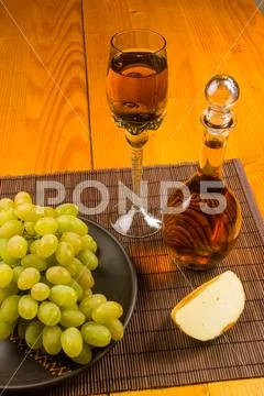 Large brush of green grapes in a ceramic plate, a decanter and a glass of win Stock Photos