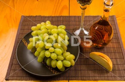 Large brush of green grapes in a ceramic plate, a decanter and a glass of win Stock Photos