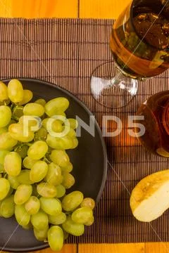Large brush of green grapes in a ceramic plate, a decanter and a glass of win Stock Photos