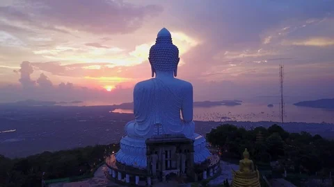 Large Buddha statue on mountain top against nice sunrise sky, aerial shot Stock Footage