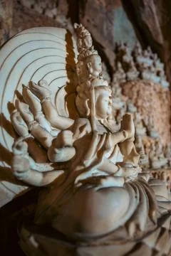 Large Buddha statue surrounded by smaller sculptures in Marble Mountains cave Stock Photos