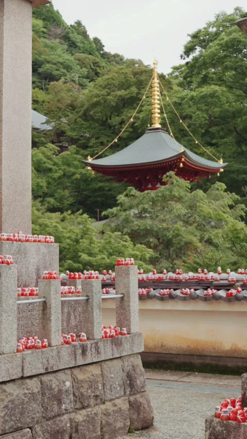 A large Buddhist statue stands peacefully in front of the vibrant red temple Stock Footage 345741044