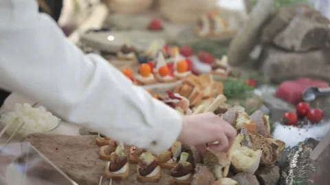 Large buffet table with snacks, waiter serves red fish sandwiches 動画素材 156676788