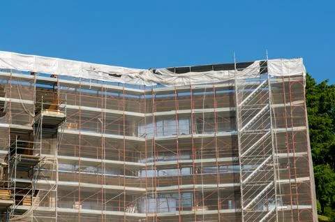 Large building facade covered in construction scaffolding under blue sky de.. 스톡 사진