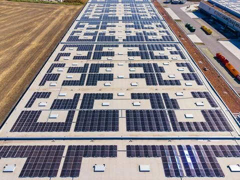 A large building features numerous solar panels arranged neatly on its roof.  库存照片