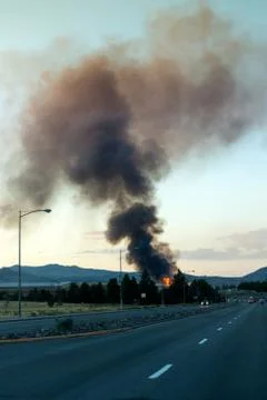 Large building fire with smoke cloud in the distance down the street Stock Photos