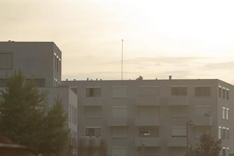 A large building with many windows is surrounded by trees and clouds Fotos de archivo