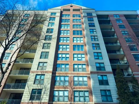 Large building with multiple floors and balconies in urban area during sunn.. Stock Photos
