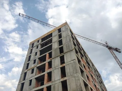 A large building under construction and a crane next to it Stock Photos