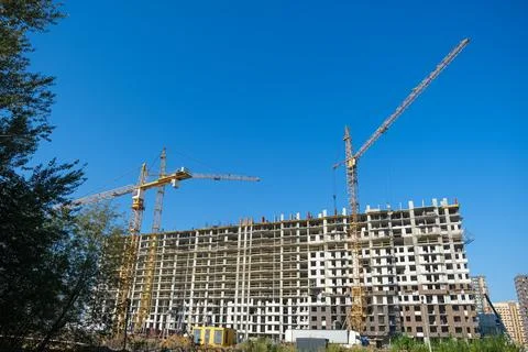 A large building under construction with cranes in the background Stock Photos