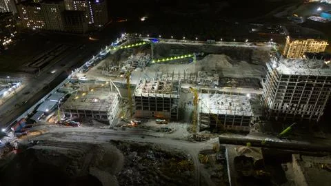 Large building under construction at night with cranes and workers Stock Photos