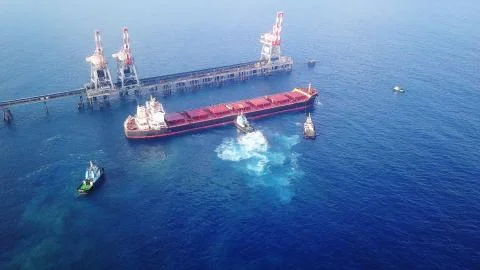 Large bulk carrier ship sailing in open ocean - aerial 4k view Stock Photos