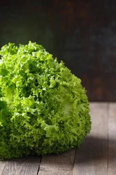 A large bunch of fresh lettuce leaves on a wooden table and a dark background Stock Photos