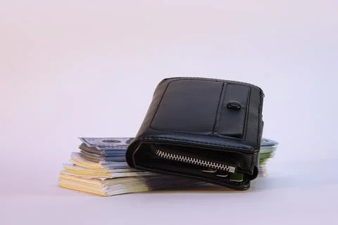 A large bundle of dollars and euros with a wallet on a light background. Stock Photos
