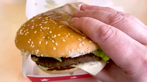 A large burger with beef, cheese, tomatoes in someone's hand Stock Footage 171725230
