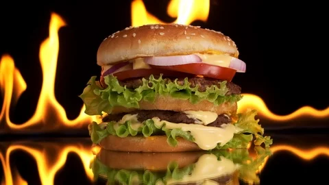 A large Burger with beef Patty, salad and vegetables ,flames in the background. Stock Footage 125655816