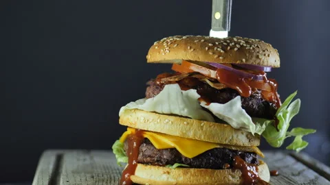 A large burger with double cutlet vegetables and a sesame bun is held together Video stock 105484670