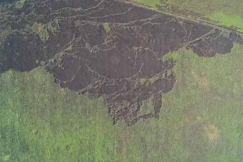 Large burnt patch with black ash on green agricultural field from missile Stock Photos