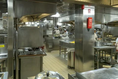 A large, bustling professional kitchen with multiple chefs. Stock Photos